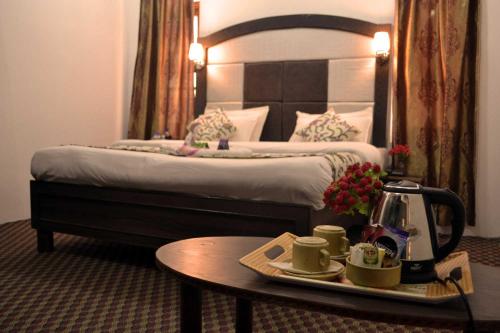 a hotel room with a bed and a table with a tray of coffeeisers at Hotel Al Azrah in Srinagar
