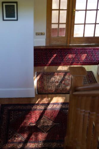 a hallway with a door and some rugs on the floor at Home Farm Oban in Oban