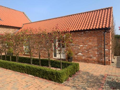 Meals Farm Holiday Cottages - The Stables في North Somercotes: مبنى من الطوب وامامه اشجار