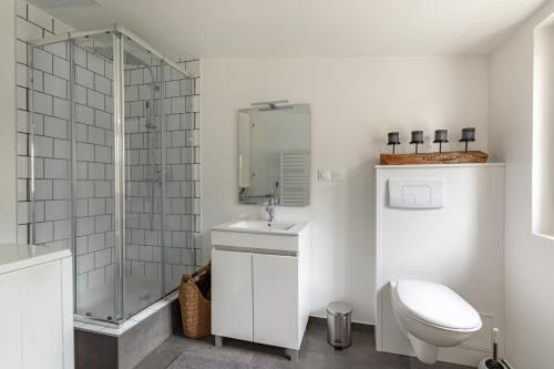 La salle de bains blanche est pourvue d'une douche et de toilettes. dans l'établissement Le Rethel, à Caen