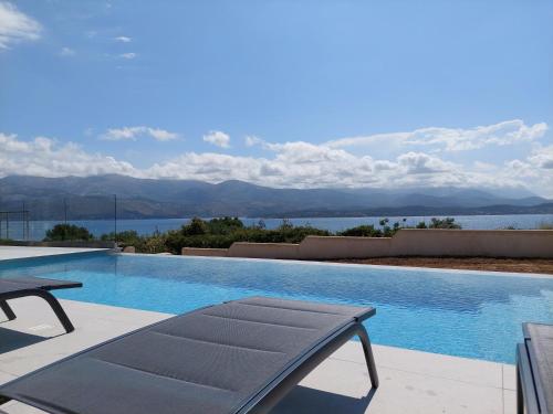 a swimming pool with a bench and a view of the water at Alekos Beach Houses-Elia Villas in Lixouri