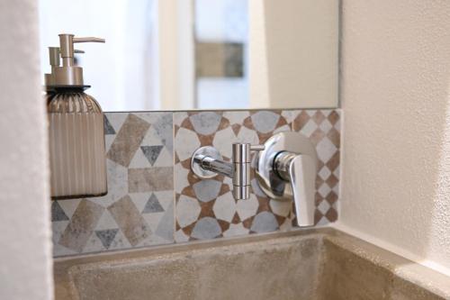 a bathroom sink with a soap dispenser on a wall at Pietra Bianca Luxury Suite Ostuni in Ostuni