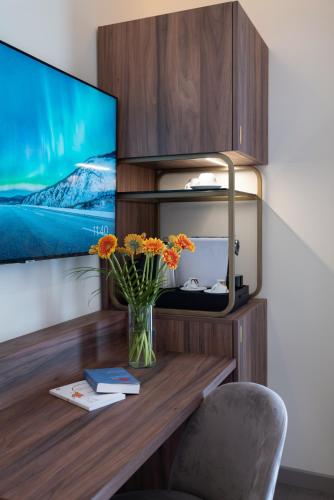 a vase of flowers sitting on a desk with a tv at 3T Boutique Hotel in Ivrea
