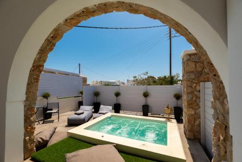 Un arco sobre una piscina en un patio. en Kasteli Suites, en Perivolos