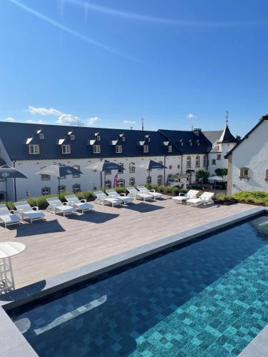 a resort with a swimming pool and lounge chairs at Chateau d'Urspelt in Urspelt