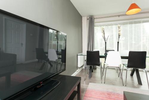 a living room with a large tv and a table and chairs at Comfortable Contractor House Gatwick: sleeps 6+ in Ifield