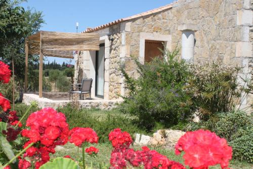 a garden with red flowers in front of a stone house at Agroturisme Es Racó De Maria in Maria de la Salut