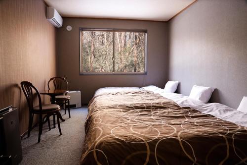 um quarto com uma cama, uma mesa e uma janela em Paper Moon em Nasu
