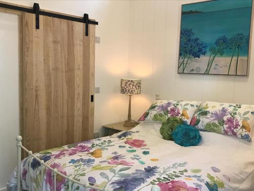 a bedroom with a bed with a floral bedspread and a lamp at The Potting Shed in St Austell