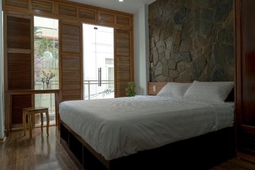 a bedroom with a large bed and a stone wall at Homestay TITO in Ho Chi Minh City