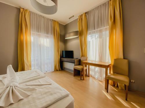 a bedroom with a bed and a desk and curtains at Royal Mediterran in Siófok