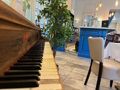 a piano in a restaurant with two chairs and a table at Le Grand Hôtel Molière in Pézenas