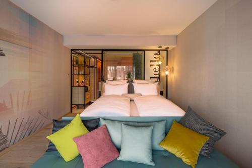 ein Schlafzimmer mit einem großen Bett mit bunten Kissen in der Unterkunft The Flamingo in Timmendorfer Strand