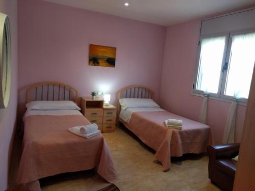 2 camas en una habitación con paredes y ventanas de color rosa en Casa Baleso, en Deltebre