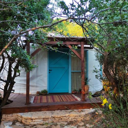 a house with a blue door on a deck at Love Frequency - יורט קסום במתת in Mattat