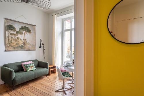a living room with a green couch and a yellow wall at Victoria Belle Vue in Saint Malo
