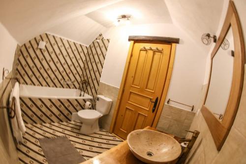 La salle de bains est pourvue de toilettes et d'une porte en bois. dans l'établissement La căsuța cu amintiri, à Vama