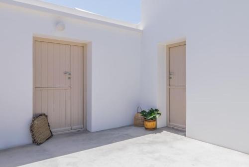 2 portes dans une chambre blanche avec une plante dans l'établissement Gazia Guesthouse Milos, à Adamas