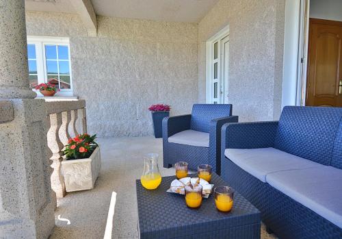 un patio con sofá azul y vasos de zumo de naranja en A Casa de Otilia, en Meaño