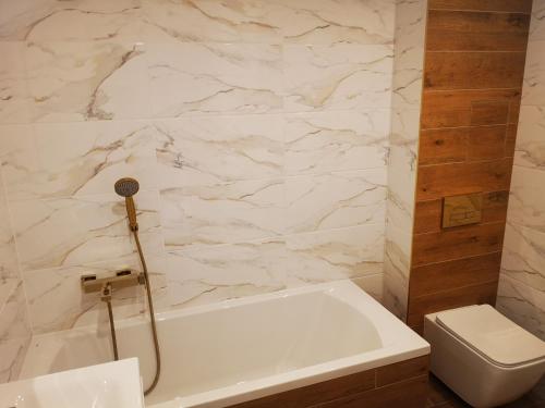 a bathroom with a white tub and a toilet at Apartament Korczaka Centrum in Suwałki