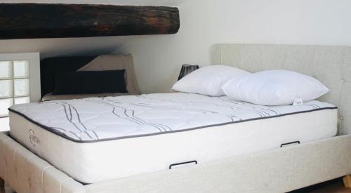 un lit avec des draps blancs et des oreillers dans une chambre dans l'établissement Duplex atypique rénové en plein centre du village, à Cassis