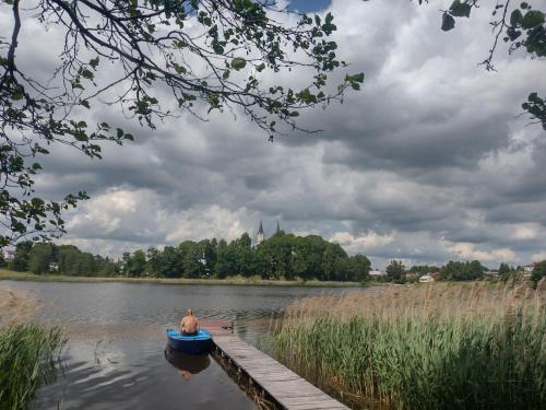 a man sitting in a boat on a lake at Willa Puńsk z basenem nad jeziorem in Puńsk