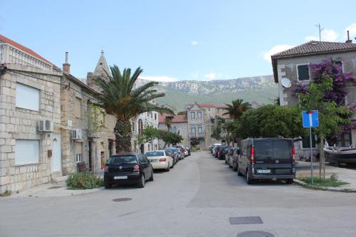 a street with cars parked on the side of the road at Stone house Castellum in Kaštela