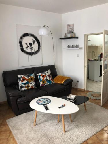 uma sala de estar com um sofá preto e uma mesa branca em Maison indépendante em Noyant-dʼAllier