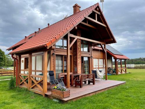 a large wooden house with a deck and a table at Kaszubska Odskocznia Ostoja Bukowo in Borowy Młyn