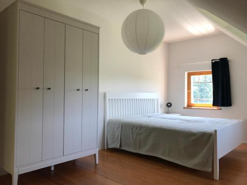 a white bedroom with a bed and a window at Ferienwohnungen Tinymoon in Feldbach