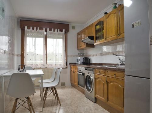 cocina con armarios de madera, mesa y lavavajillas en La Villa De Lore, Piso Completo Apto 6 Personas, en Avilés