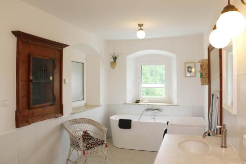 een witte badkamer met een bad en een wastafel bij Ferienwohnungen Tinymoon in Feldbach