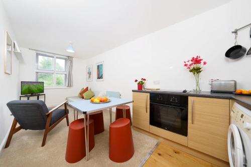 een keuken met een tafel en een kleine keuken met een eetkamer bij Central Hackney Apartment in Londen
