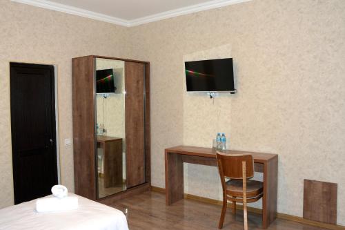 Habitación de hotel con escritorio y TV en la pared en Tulpan Hotel, en Sheki