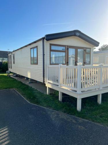 a small white trailer with a porch on the grass at Seascape Horizon at Camber Sands in Camber
