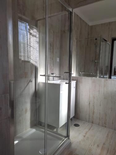 a bathroom with a glass shower and a sink at Estombar Novo in Estômbar