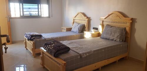 two twin beds in a room with a window at appartement boukidan in Al Hoceïma