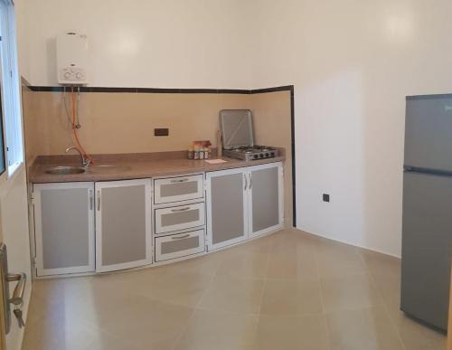 una cucina vuota con armadi bianchi e frigorifero di appartement boukidan ad Al-Ḥoseyma