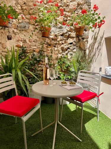 - une table avec 2 chaises et une bouteille de vin dans l'établissement Les Petits Volets 3 appartements au choix, à Antibes
