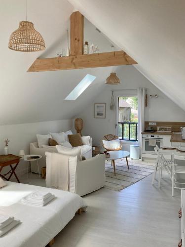 een woonkamer met witte meubels en een zolder bij Studio cosy avec coin jardin in Lancieux