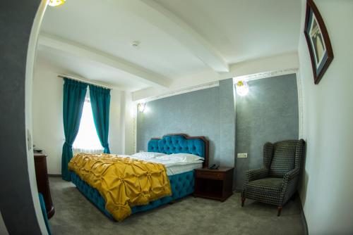 a bedroom with a blue bed and a chair at Voila Inn Predeal in Predeal
