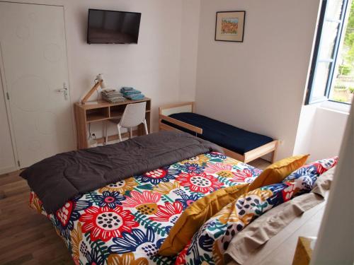 a bedroom with a bed and a desk with a television at Gites de l'écluse "Au fil de l'Aude" in Sallèles-dʼAude