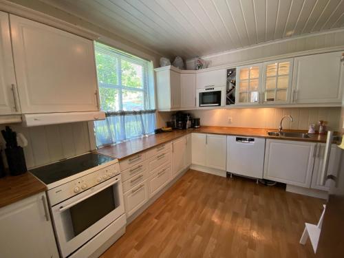 a kitchen with white cabinets and a wooden floor at Sentral tomannsbolig ved park, Rjukan in Rjukan