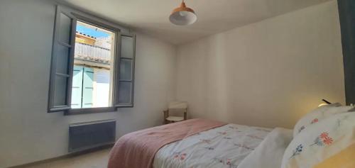 une chambre avec un lit et une fenêtre dans l'établissement La maison du grand clar arles, à Arles