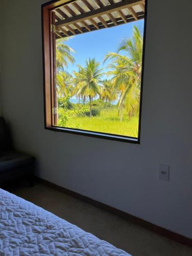 a bedroom with a window with a view of palm trees at Casa Praia Patacho in Pôrto de Pedras