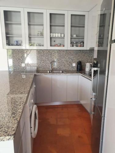 a kitchen with white cabinets and a wooden floor at Citrus Tree House, private pool and garden. in Angeja