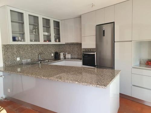 a kitchen with white cabinets and a stainless steel refrigerator at Citrus Tree House, private pool and garden. in Angeja