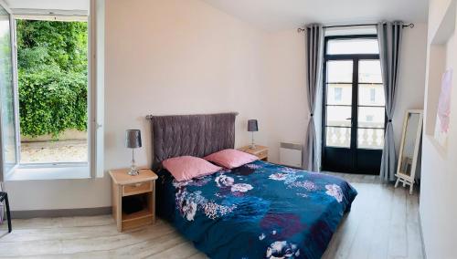 um quarto com uma cama com um edredão azul e uma janela em Appartement cour ancienne abbaye em Saint-Astier