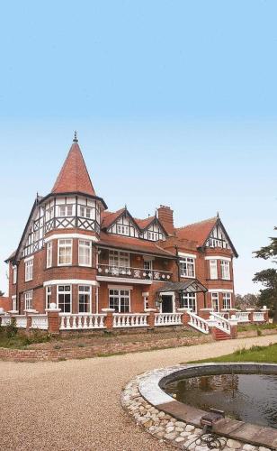 a large brick building with a pond in front of it at The Grange Hotel in Kings Lynn