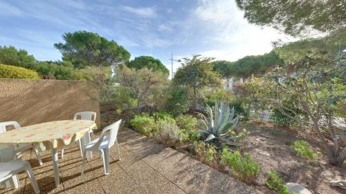 d'une terrasse avec une table et des chaises dans le jardin. dans l'établissement Gruissan: Maisonnette T2 avec jardin, à Gruissan